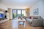 Wohnzimmer mit Schlafcouch, Sesseln, TV und Blick zur Terrasse - Wohnung 05-3 - Top-Hundeurlaub