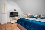 Schlafzimmer mit Doppelbett, Babybett und TV - Doppelhaushälfte 9a - Leuchtturm - Top-Hundeurlaub