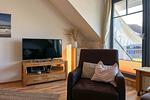 Wohnzimmer mit Sessel und TV - Wohnung 08-7 - Top-Hundeurlaub