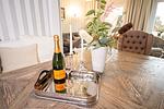 Nautic Lounge – Beach View: Champagner & Gläser auf stilvollem Esstisch mit Blumendeko. - Nautic Lounge  - Beach View - Top-Hundeurlaub