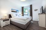 Schlafzimmer mit Boxspringbett mit TV - Aparthotel Ostseeallee 4-30 - Top-Hundeurlaub
