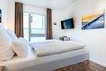 Schlafzimmer mit Boxspringbett und TV - Aparthotel Ostseeallee 4-31 - Top-Hundeurlaub