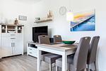 Wohn-/Essbereich mit Tisch, Sitzgelegenheiten und TV - Aparthotel Ostseeallee 4-34 - Top-Hundeurlaub