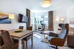 Wohn-/Essbereich mit Sitzgelegenheiten, TV und Zugang zum Balkon - Aparthotel Ostseeallee 4-35 - Top-Hundeurlaub