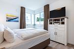 Schlafzimmer mit Boxspringbett (1,80 x 2,00 m), Kommode und TV - Aparthotel Ostseeallee 4-38 - Top-Hundeurlaub