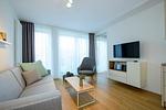 Wohn-Essbereich mit Couch, Couchtisch, Sessel und TV - Apartmentvilla Anna See 1-14 - Top-Hundeurlaub