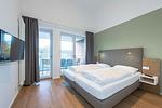 Schlafzimmer mit Boxspringbett und TV - Apartmentvilla Anna See 3-08 - Top-Hundeurlaub
