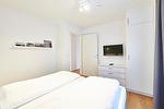 Schlafbereich mit Doppelbett und Flatscreen TV - Deichhäuser Anna Küste 3-30 - Top-Hundeurlaub