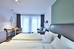 Wohn-Ess-Schlafbereich mit Sofa, Esstisch, Sitzgelegenheit und Doppelbett sowie Zugang zum Balkon - Deichhäuser Anna Küste 4-22 - Top-Hundeurlaub