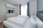 Schlafzimmer mit Doppelbett, Kleiderschrank und Flatscreen-TV - Deichhäuser Anna Küste 6-10 - Top-Hundeurlaub