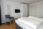 Schlafzimmer mit Doppelbett, Kleiderschrank und Flatscreen TV - Deichhäuser Anna Küste 6-31 - Top-Hundeurlaub