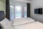 Schlafzimmer mit Doppelbett, Flatscreen-TV und Zugang zur Terrasse - Deichhäuser Anna Küste 7-13 - Top-Hundeurlaub
