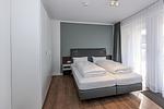 Schlafzimmer mit Doppelbett, Kleiderschrank und Zugang zur Terrasse - Deichhäuser Anna Küste 7-14 - Top-Hundeurlaub