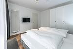 Schlafzimmer mit Doppelbett, Kleiderschrank und Flatscreen TV - Deichhäuser Anna Küste 7-14 - Top-Hundeurlaub