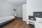 Schlafzimmer mit zwei Einzelbett und Sitzgelegenheit - Deichhäuser Anna Küste 7-14 - Top-Hundeurlaub