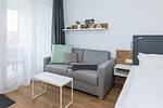 Wohn-Ess-Schlafbereich mit Sofa, Esstisch, Sitzgelegenheit und Doppelbett sowie Zugang zum Balkon - Deichhäuser Anna Küste 7-22 - Top-Hundeurlaub