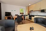 Wohn/Essbereich mit Couch, Kaminofen und Küchenzeile - Urlauberdorf 55b - Top-Hundeurlaub