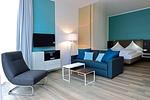 Wohn/ Essbereich mit Couch, Tisch und Fernseher - Aparthotel Anna Düne 0-11 - Top-Hundeurlaub