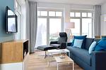 Wohn/ Essbereich mit Couch, Sessel und Fernseher - Aparthotel Anna Düne 2-27 - Top-Hundeurlaub