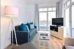 Wohn/ Essbereich mit Couch, Tisch und Fernseher - Aparthotel Anna Düne 2-33 - Top-Hundeurlaub