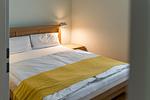 Schlafzimmer mit Doppelbett und gelber Bettdecke - Haus am Schilf - Wohnung 5 - Top-Hundeurlaub
