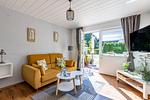 Helles Wohnzimmer mit Sofa und Fenstern - Sonnenblumenhaus 01 - Top-Hundeurlaub