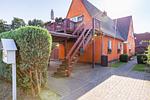 Außenansicht eines orangefarbenen Hauses mit Balkon - Sonnenblumenhaus 02 - Top-Hundeurlaub