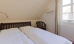 Schlafzimmer mit Doppelbett und Holzstuhl - Klönhus - Top-Hundeurlaub