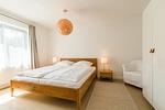 Helles Schlafzimmer mit Doppelbett und Stuhl - Drei Akazien Wohnung 1 - Top-Hundeurlaub