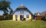Außenansicht eines gelben Hauses mit Terrasse - Hus in de Wieck 01 - Top-Hundeurlaub