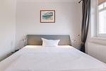 Schlafzimmer mit Doppelbett und Bildern an der Wand. - Strandläufer 02 - Top-Hundeurlaub