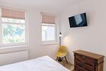 Schlafzimmer mit Bett, Fernseher und Schreibtischstuhl. - Strandläufer 02 - Top-Hundeurlaub