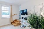 Innenansicht eines Wohnzimmers mit Fernseher und Holztreppe. - Strandläufer 01 - Top-Hundeurlaub
