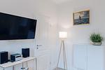 Wohnzimmer mit Fernseher, Regal und Stehlampe. - Strandläufer 01 - Top-Hundeurlaub