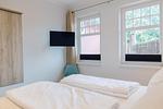 Schlafzimmer mit zwei Betten und Fernseher an der Wand. - Strandläufer 01 - Top-Hundeurlaub