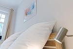 Ein Schlafzimmer mit einem Holzbettrahmen und weißen Kissen. - Strandläufer 01 - Top-Hundeurlaub
