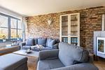 Geräumiges Wohnzimmer mit grauen Sofas und Kamin - Strandhaus Wustrow - Wohnung 1 - Top-Hundeurlaub