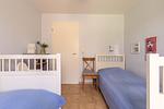 Schlafzimmer mit zwei Einzelbetten und Stuhl - Strandhaus Wustrow - Wohnung 1 - Top-Hundeurlaub