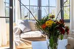 Helles Wohnzimmer mit gemütlichem Sofa und Blumendekoration - Strandhaus Wustrow - Wohnung 4 - Top-Hundeurlaub