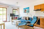Helles Wohnzimmer mit blauem Sofa und Fernseher - Windrose 09 - Top-Hundeurlaub