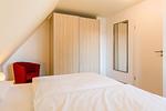 Schlafzimmer mit Doppelbett und rotem Sessel - An den Boddenwiesen 01 - Top-Hundeurlaub