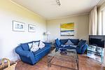 Helles Wohnzimmer mit blauen Sofas und Glastisch - Boddenzauber 01 - Top-Hundeurlaub
