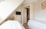 im ersten Schlafzimmer im App. 12 im Haus Carmen in Wenningstedt stehen zwei Einzelbetten und ein TV hängt an der Wand - Haus Carmen App. 12 - Top-Hundeurlaub