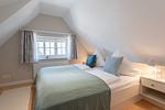 im Schlafzimmer steht ein Doppelbett mit Tagesdecke und Kissen in Haus Carmen App. 12 in Wenningstedt - Haus Carmen App. 12 - Top-Hundeurlaub
