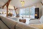 Offenes Wohnzimmer mit Couch, Meerblick, Ofen und Essbereich - Westscheune am Mühlendamm - Top-Hundeurlaub