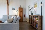 Offenes Wohnzimmer mit Couch, Meerblick, Ofen und Essbereich - Westscheune am Mühlendamm - Top-Hundeurlaub