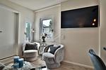 Nautic Lounge – Beach Garden: Helle Sitzecke mit TV und Panoramafenster im modernen Apartment Haffkrug. - Nautic Lounge - Beach Garden - Top-Hundeurlaub