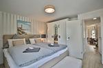 Nautic Lounge – Beach Garden: Schlafzimmer mit Doppelbett, Schrank im Landhausstil und Blick ins Apartment Haffkrug. - Nautic Lounge - Beach Garden - Top-Hundeurlaub