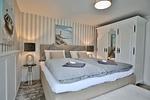 Nautic Lounge – Beach Garden: Helles Schlafzimmer mit Boxspringbett, großem Kleiderschrank & maritimer Deko in Haffkrug. - Nautic Lounge - Beach Garden - Top-Hundeurlaub