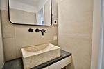 Nautic Lounge – Beach Garden: Stylisches Bad mit Naturstein-Waschbecken und großem Spiegel im Apartment Haffkrug. - Nautic Lounge - Beach Garden - Top-Hundeurlaub